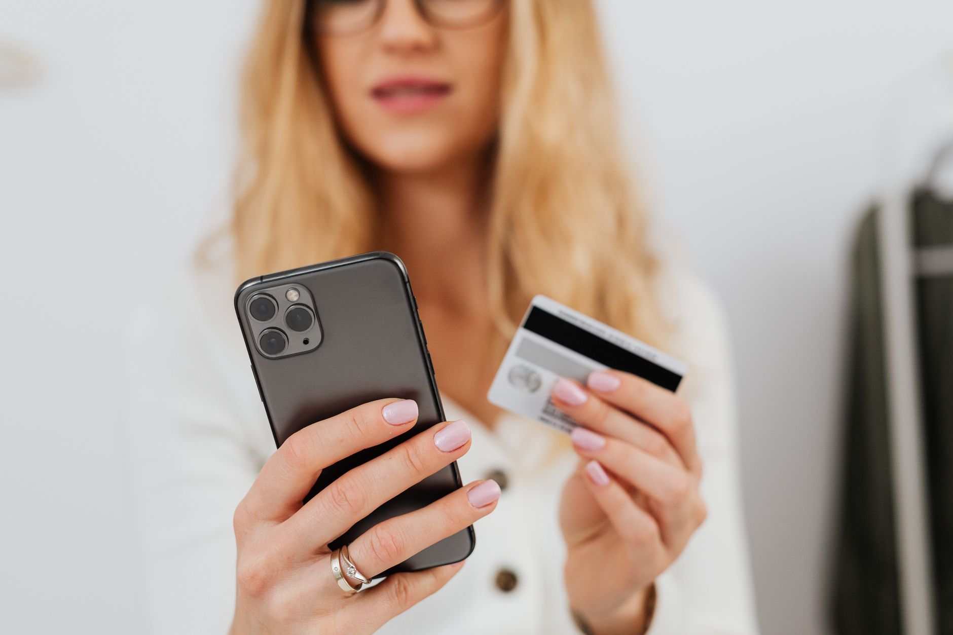 Une personne tient un smartphone dans une main et une carte bancaire dans l'autre