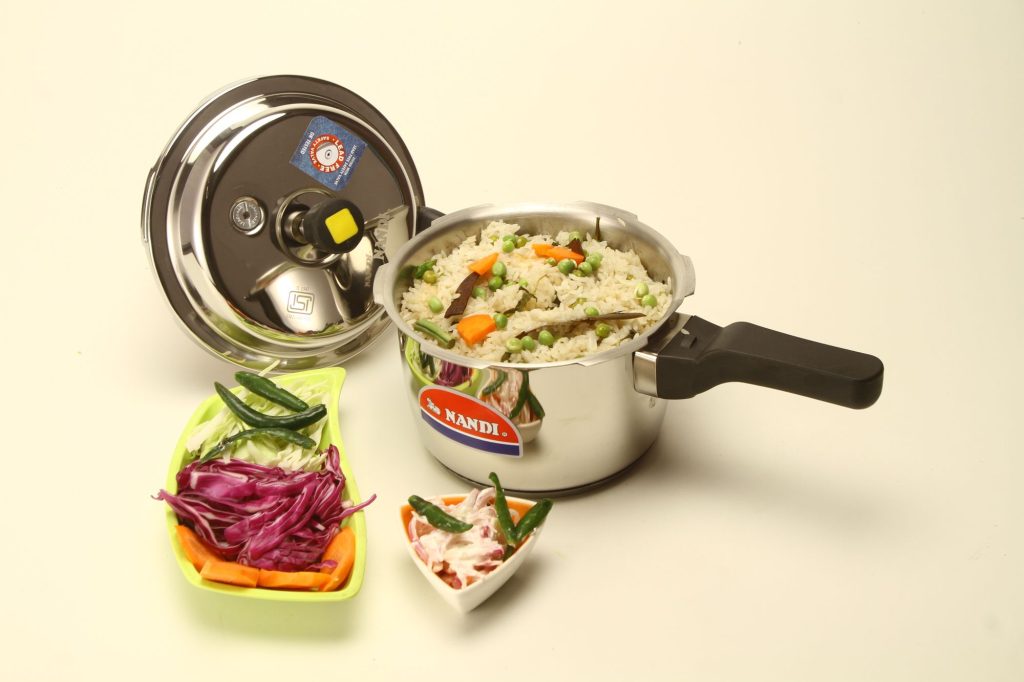 Autocuiseur en inox avec son couvercle, rempli de riz aux légumes