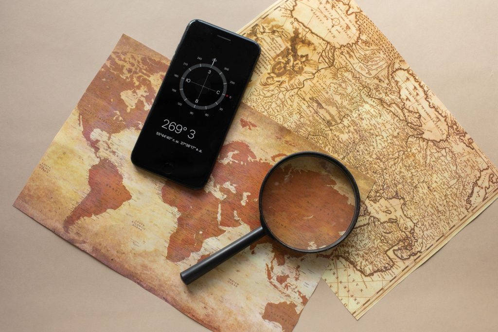 Smartphone et loupe posés sur une carte du monde ancienne en papier