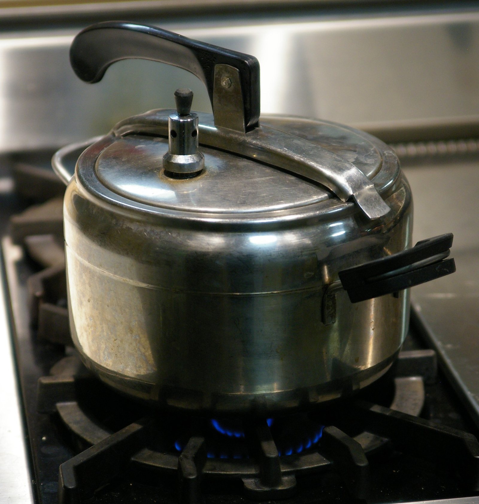 Cocotte-minute en aluminium sur un feu de cuisinière à gaz, avec sa soupape sur le couvercle