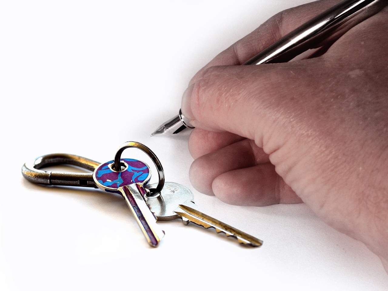 Main qui signe un contrat de location, trousseau de clés posé à côté