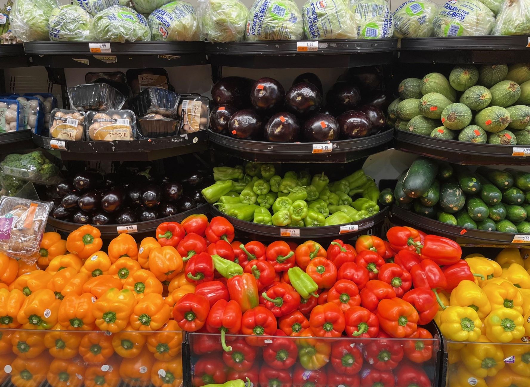 Rayon de fruits et légumes d’un supermarché avec poivrons, aubergines, concombres et salades