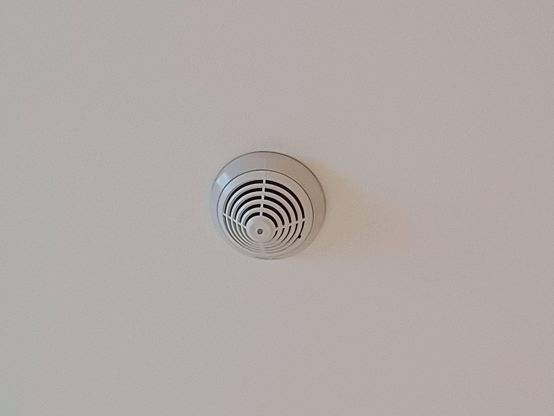 Boîtier rond blanc à grille fixé au plafond d’un couloir
