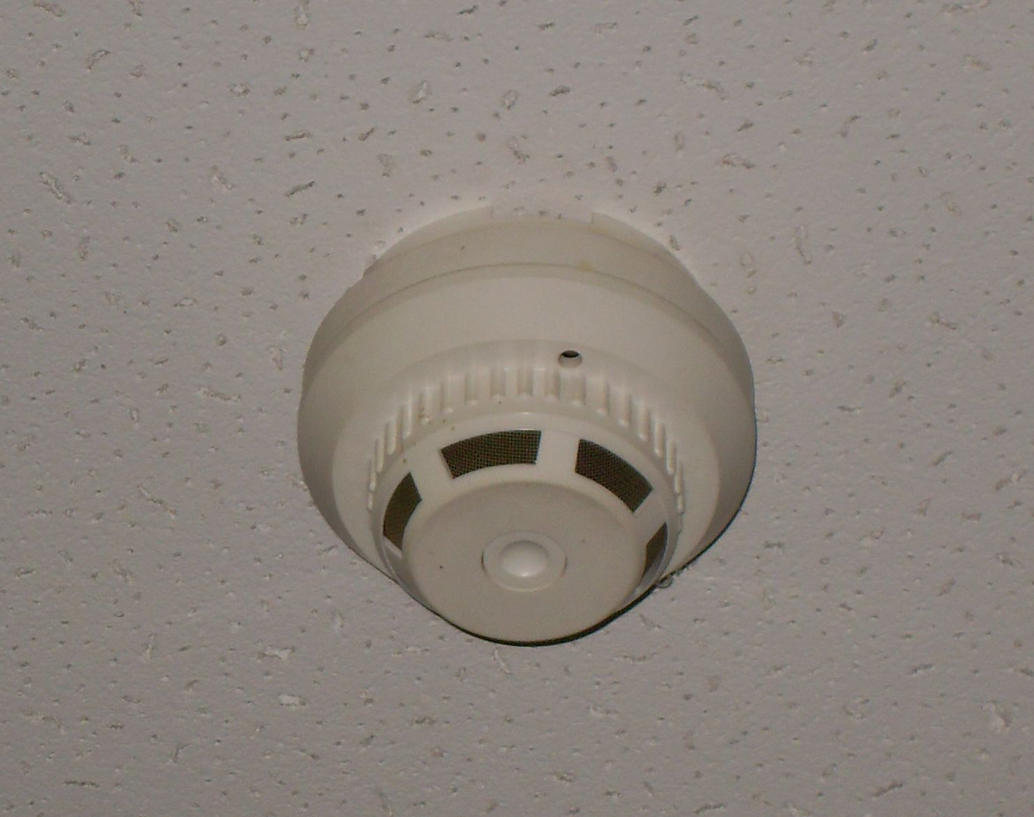 Détecteur de fumée blanc fixé au plafond, vu de dessous