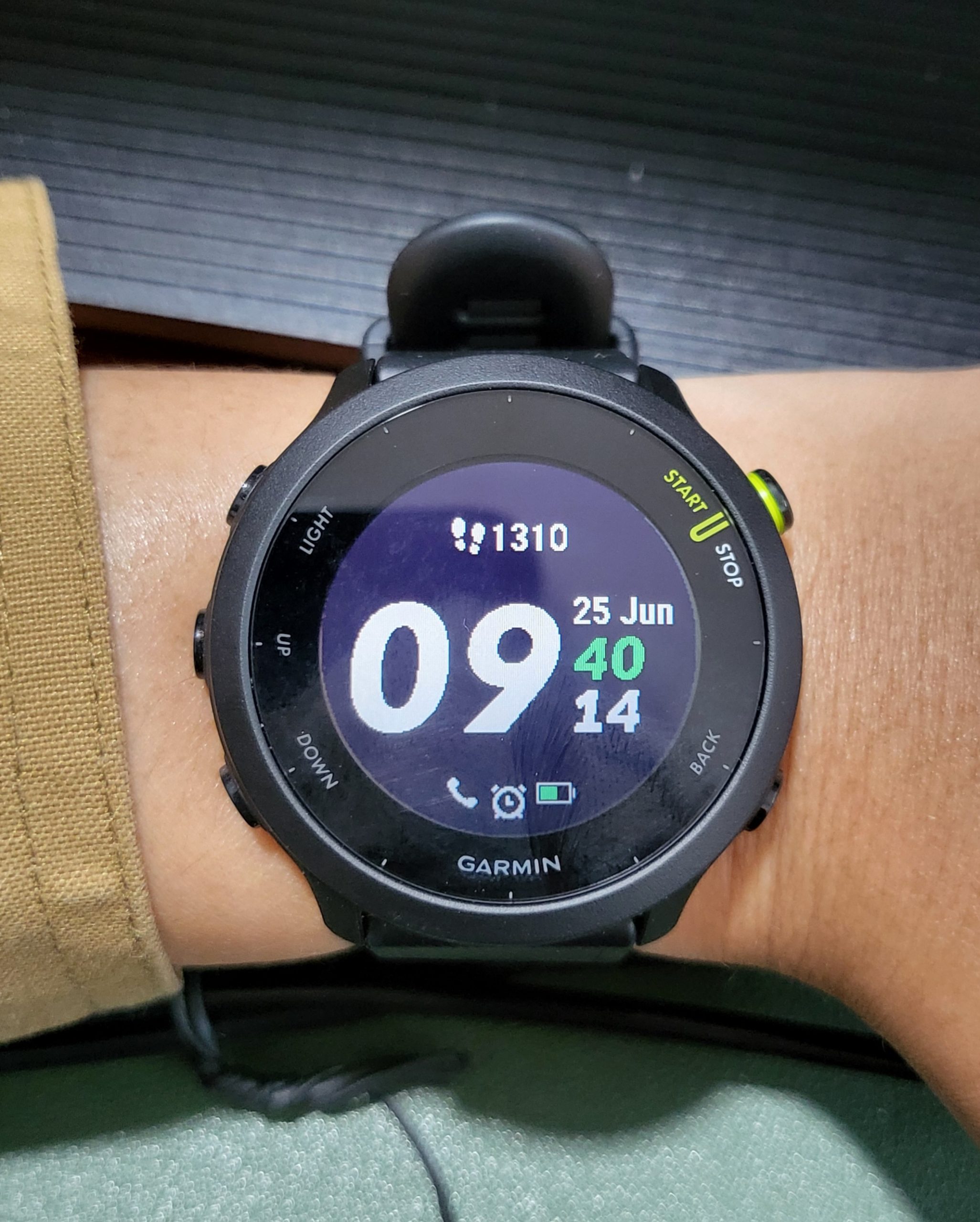Montre Garmin Forerunner 55 noire au poignet affichant l'heure, la date et le nombre de pas