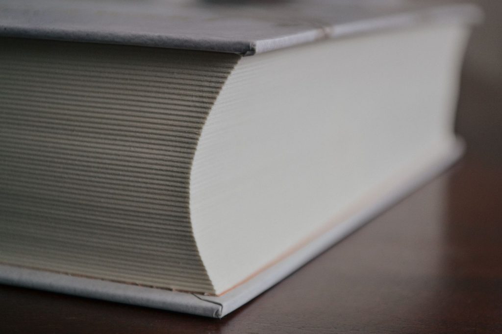 Gros plan sur un livre très épais à couverture rigide grise posé sur une table en bois