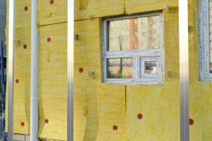 Murs en rénovation garnis de panneaux d'isolant jaune en laine minérale, avec une fenêtre