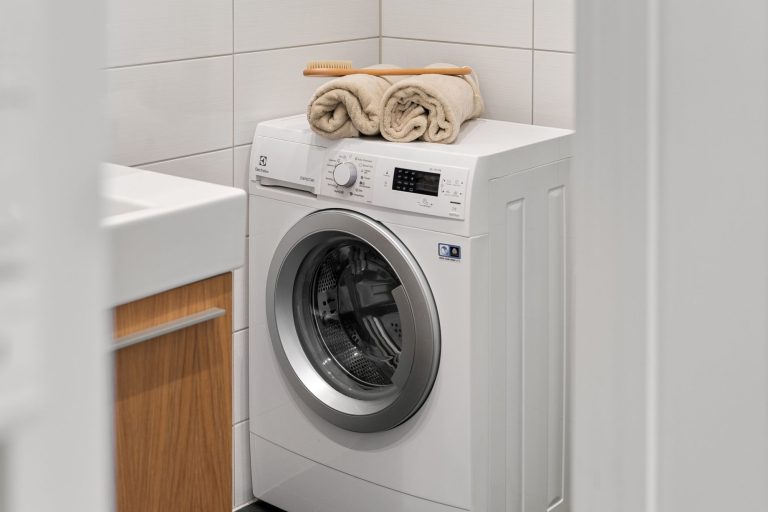 Lave-linge à hublot dans une buanderie, avec des serviettes pliées dessus