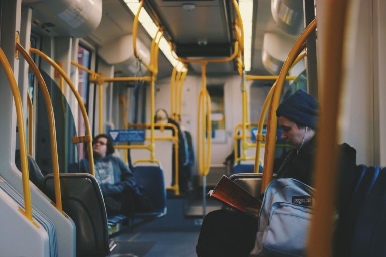 Voyageurs assis dans un tramway, l’un d’eux lisant un livre