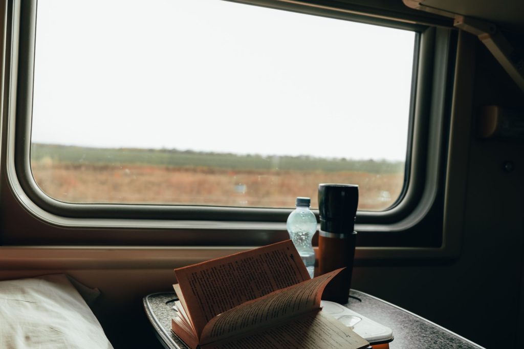 Livre ouvert posé près de la fenêtre d'un compartiment de train, paysage de campagne dehors