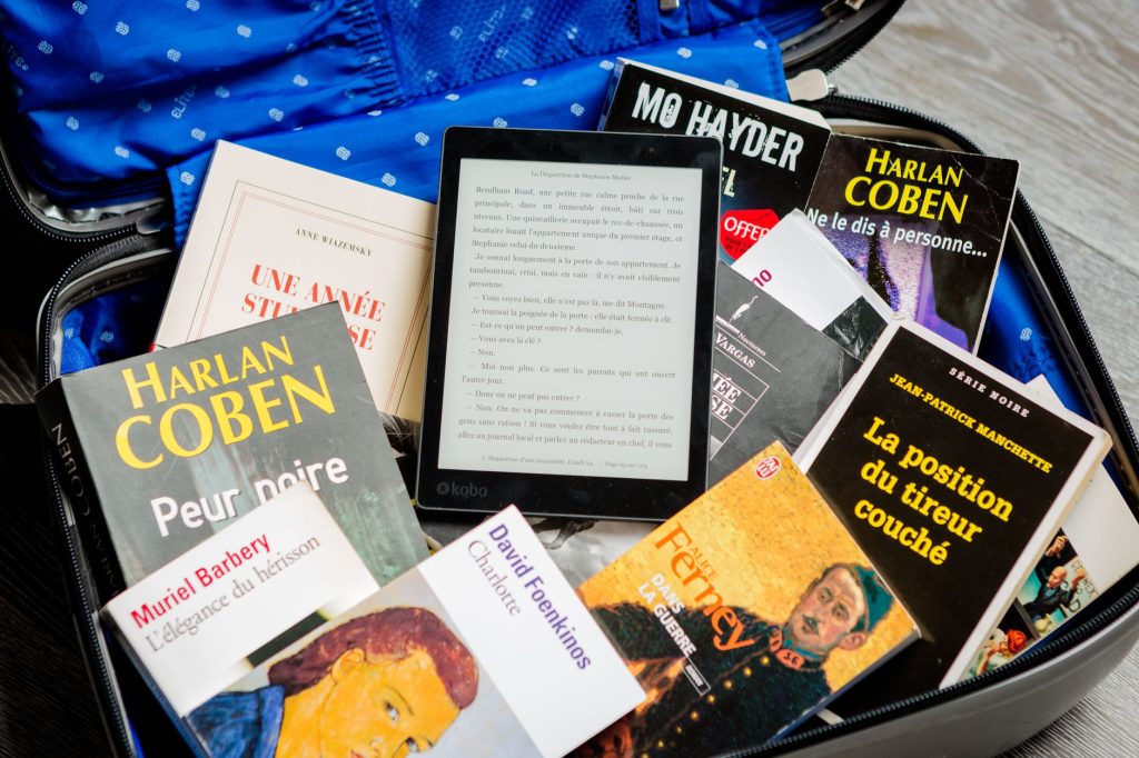 Valise ouverte remplie de livres de poche et d'une liseuse, prête pour un court séjour