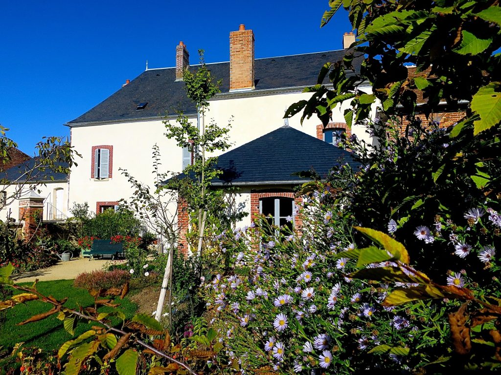 La maison de Colette côté jardin à Saint-Sauveur-en-Puisaye, avec ses fleurs au premier plan
