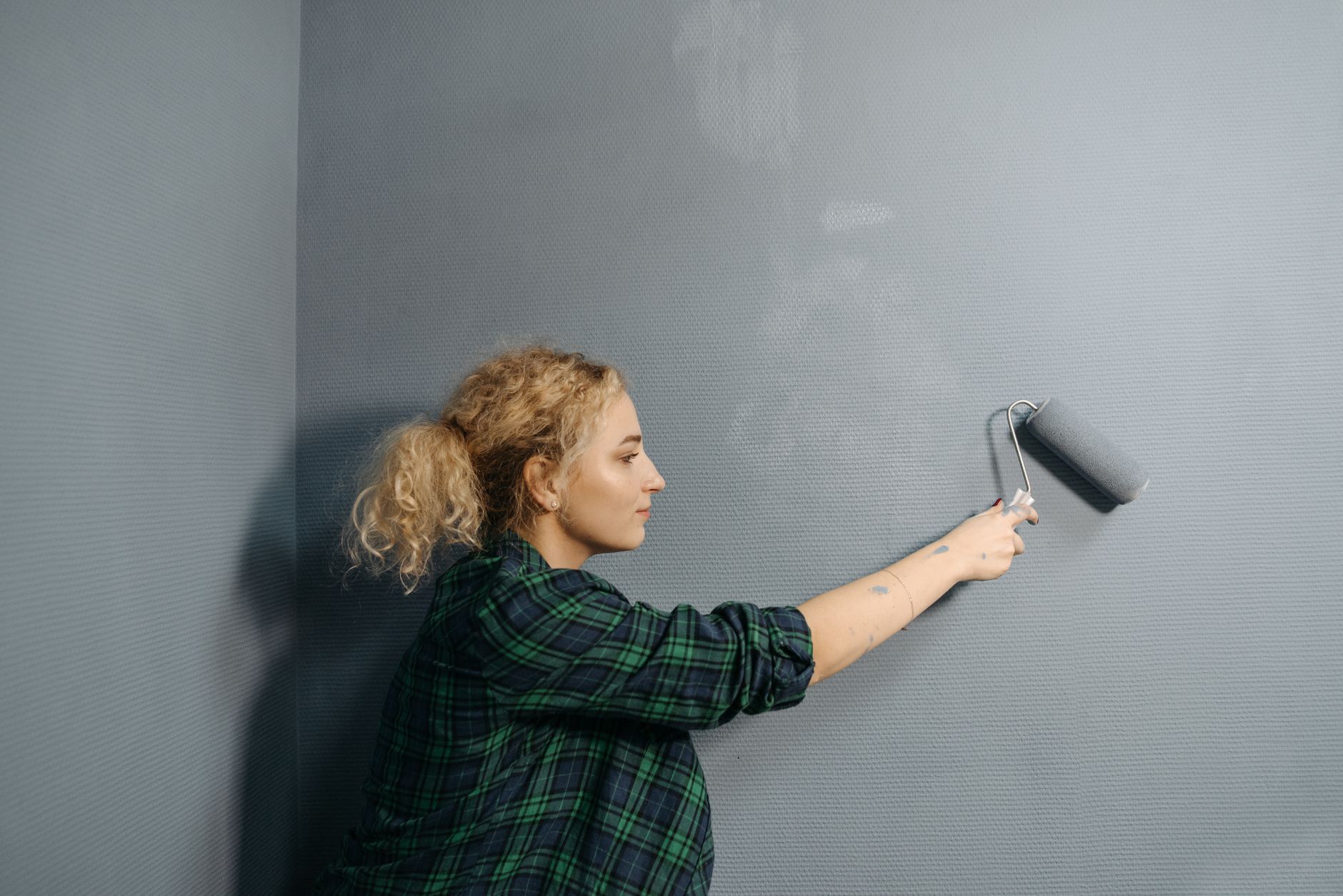 Femme peignant un mur gris au rouleau