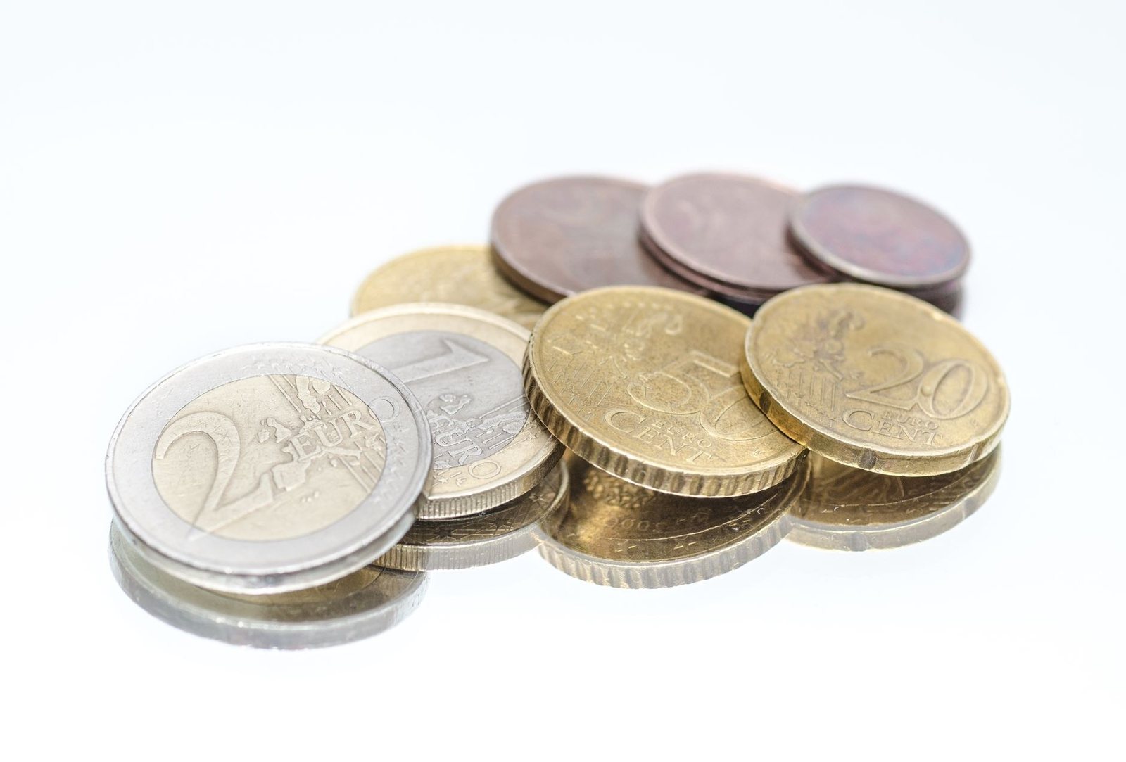 Pièces de monnaie en euros, de 1 centime à 2 euros, posées en petit tas sur un fond blanc