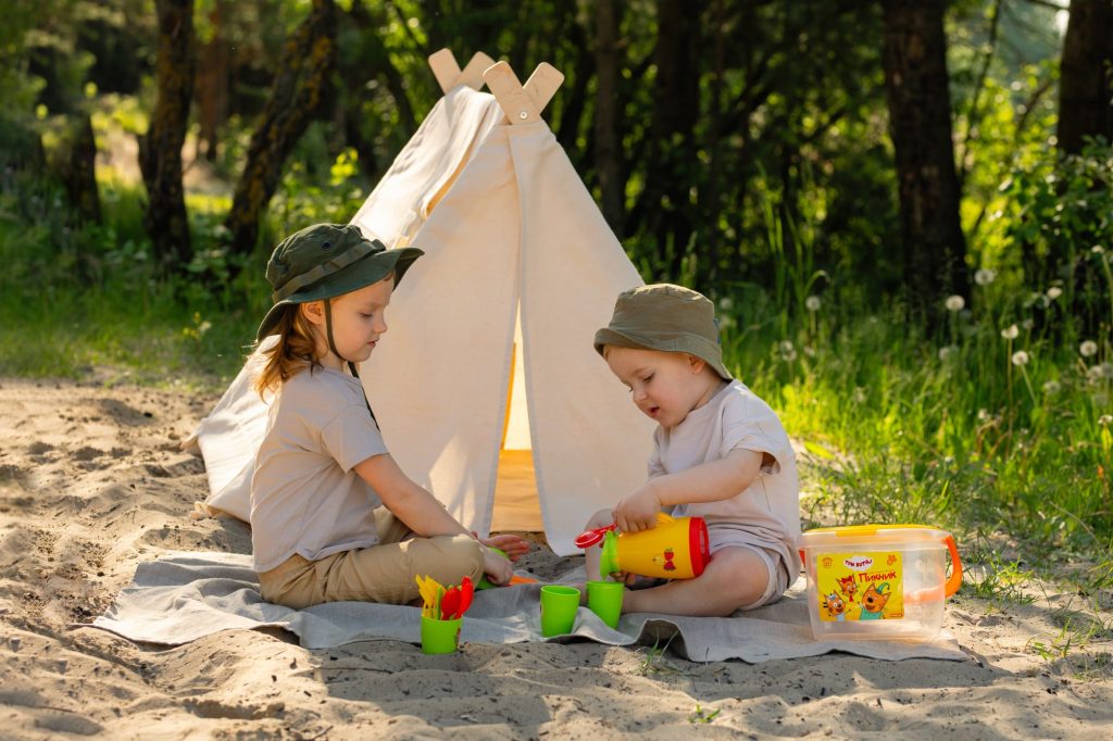 Deux enfants jouent dans un tipi sur le sable d'une plage