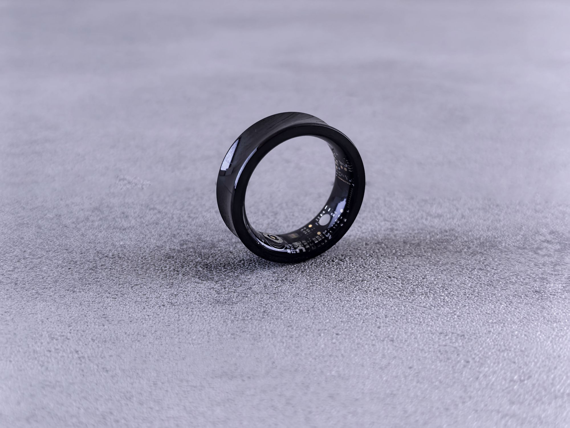 Bague connectée noire posée sur une surface grise, objet de suivi du sommeil