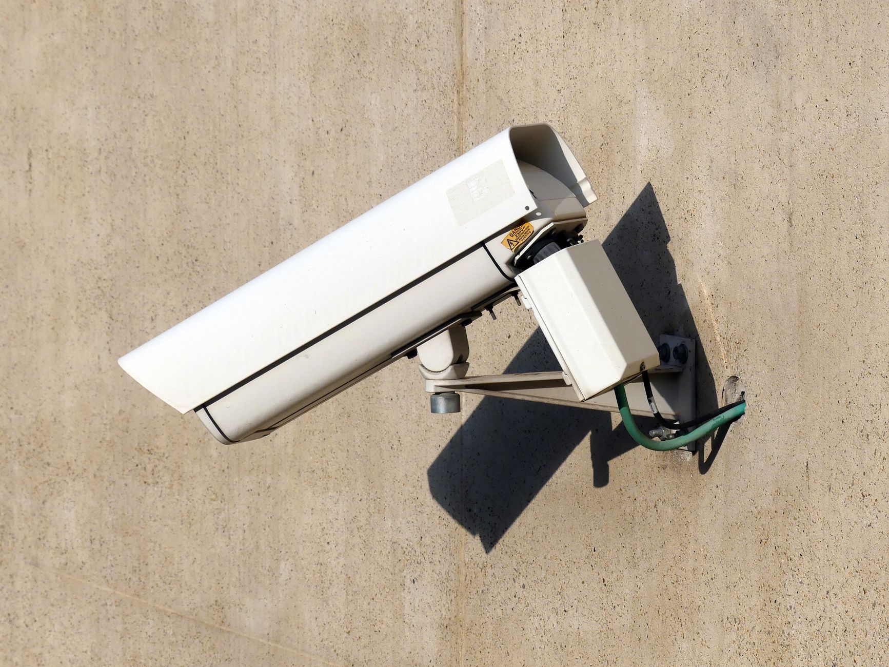 Caméra de surveillance extérieure blanche en boîtier, fixée sur un mur de façade
