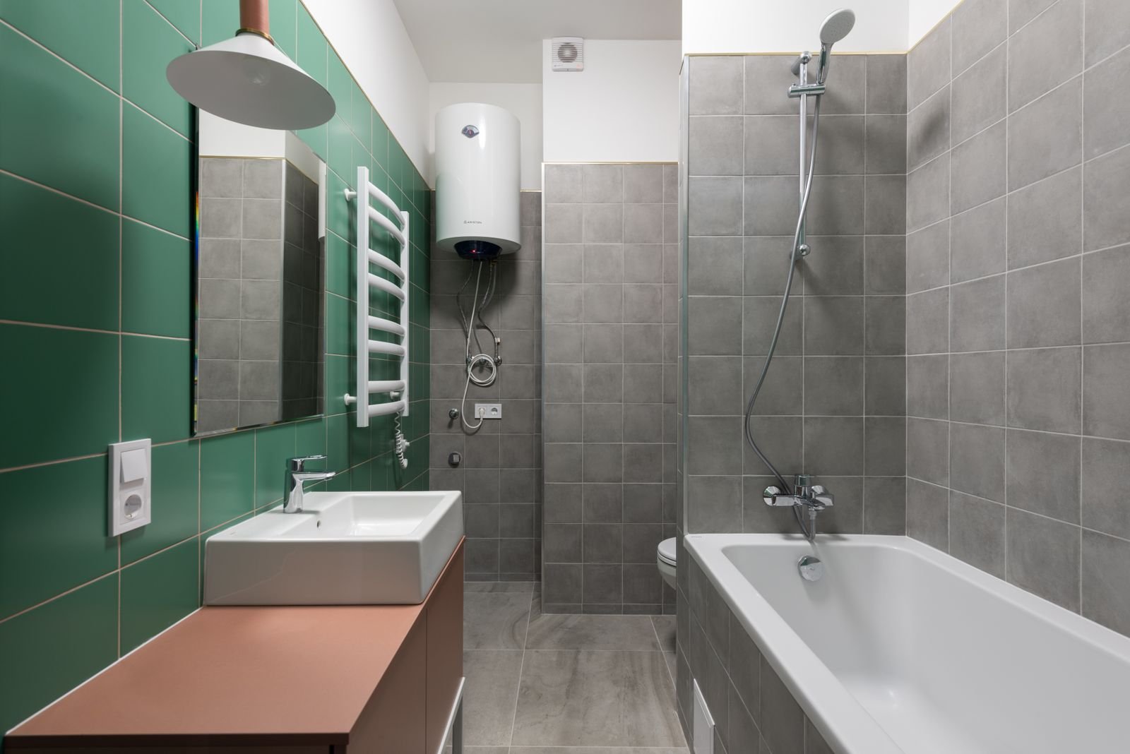 Ballon de chauffe-eau fixé au mur d'une salle de bains, près d'un lavabo et d'une baignoire