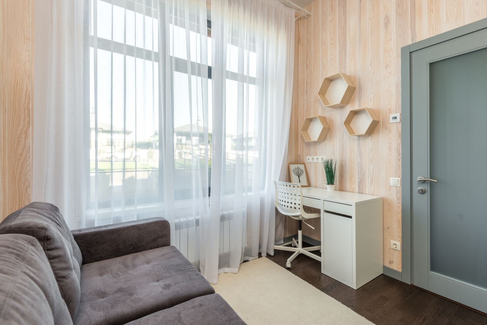 Petit bureau blanc avec une chaise installé dans un coin de salon, à côté d'une grande fenêtre