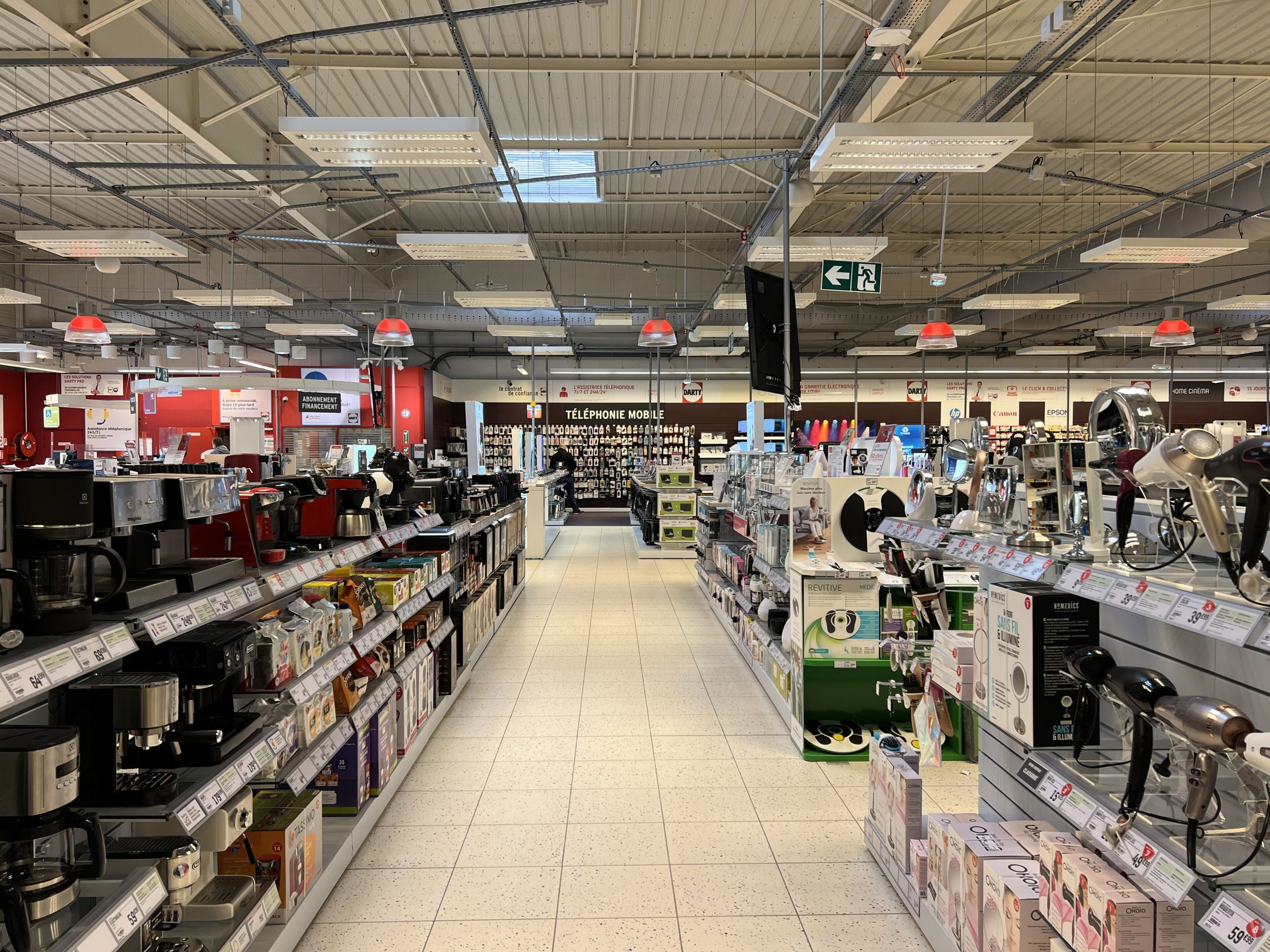 Allée d'un magasin Darty avec des machines à café et des sèche-cheveux en rayon, étiquettes de prix en euros