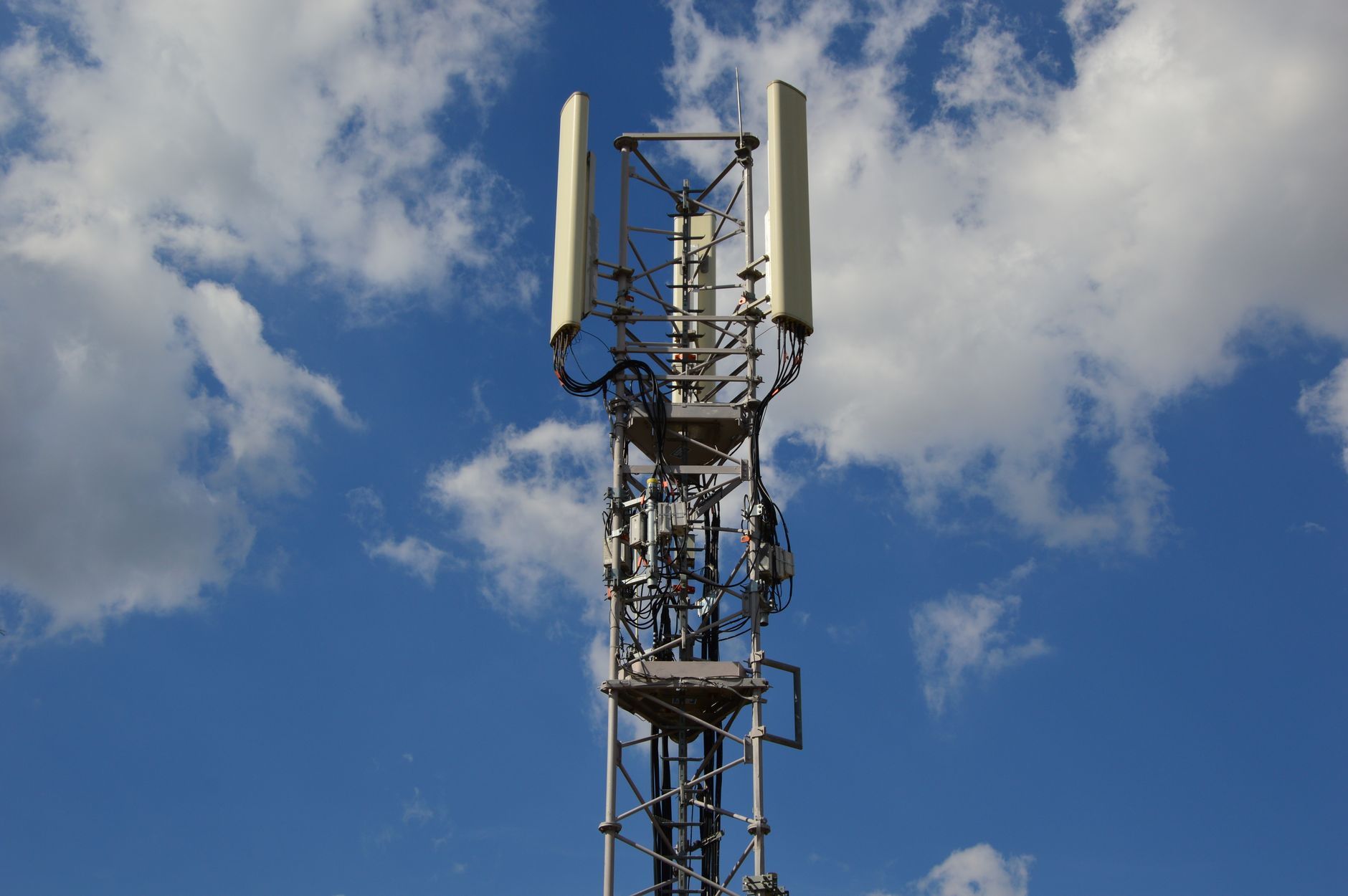 Pylône d’antenne-relais mobile équipé d’antennes sectorielles sous un ciel bleu nuageux
