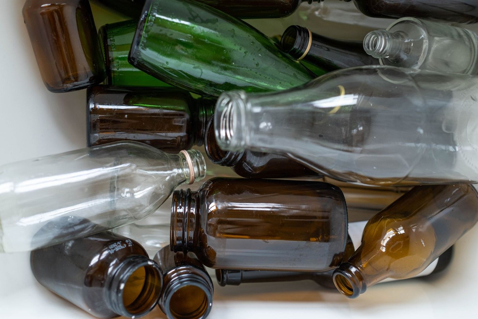 Bouteilles et bocaux en verre vides, transparents, verts et bruns, rassemblés dans un bac