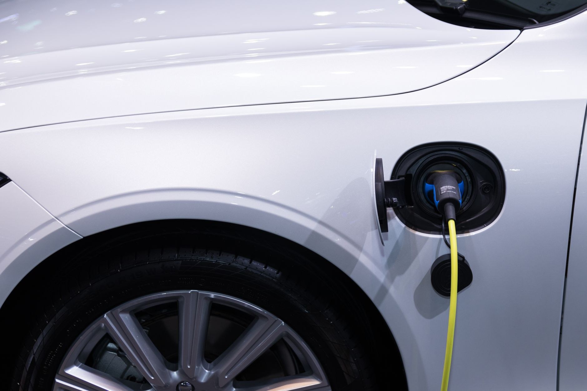 Voiture blanche en charge : un câble jaune branché sur la trappe de recharge, près de la roue avant